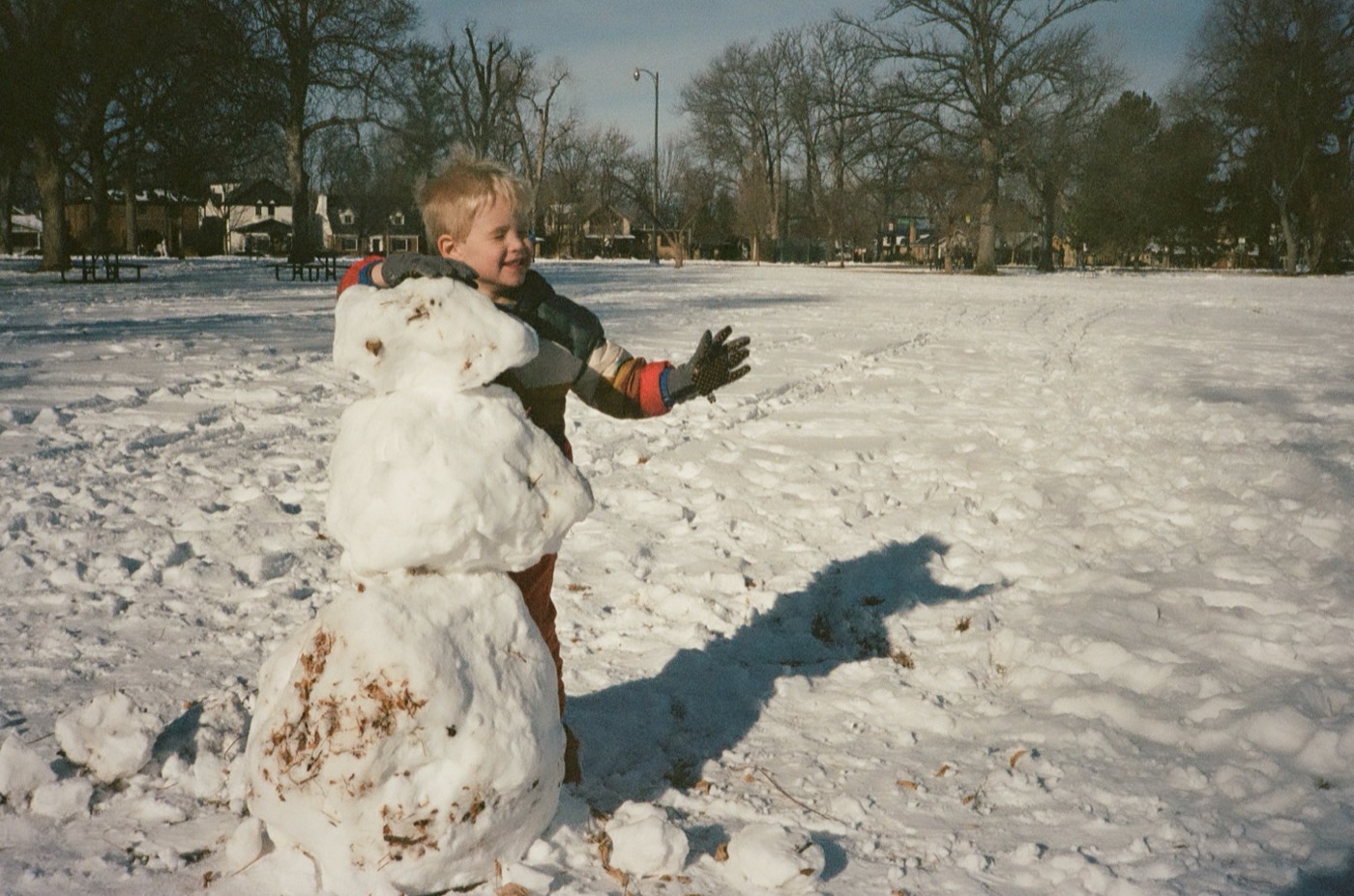 Bryce with his arm around a snowman he built in a snowy park